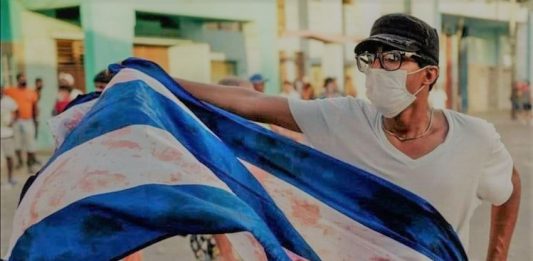 Manifestante levanta una bandera ensangrentada, el pasado 11 de julio durante la revuelta popular en Cuba. (Foto original: AFP)