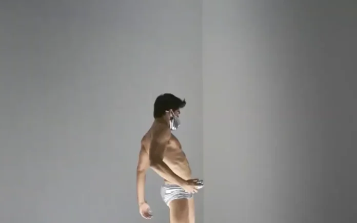 un bailarín con slip plateado y mascarilla sobre la plataforma iluminada de ‘Untitled’ (Go-Go Dancing Platform) de Félix González-Torres.