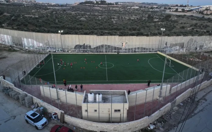 Cancha de fútbol junto al muro de separación israelí en el campo de refugiados de Aida, en Belén, donde opera el Lajee Center, nominado al Premio Astrid Lindgren 2027.