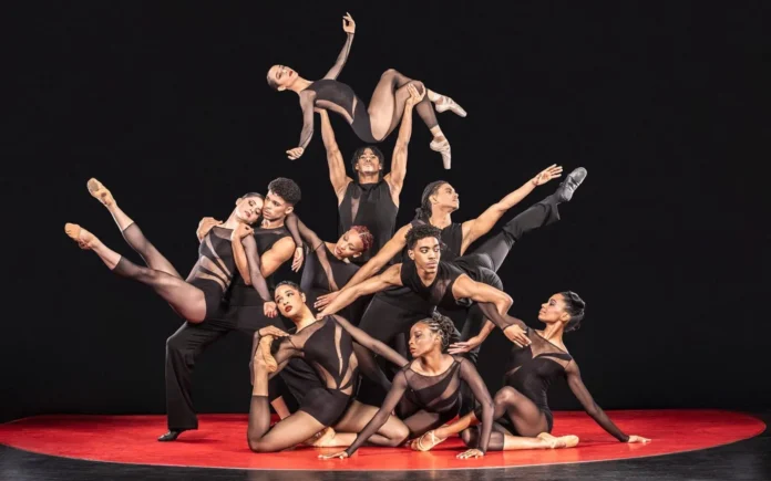 Elenco de bailarines de Acosta Danza en mallas negras formando una pirámide sobre un círculo rojo, en la imagen promocional de ‘Cuban Baroque’.