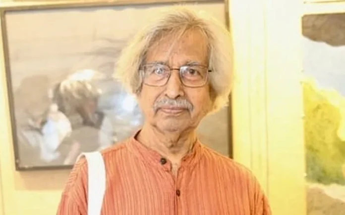 Jogen Chowdhury, de camisa naranja, ante obras enmarcadas en una exposición.