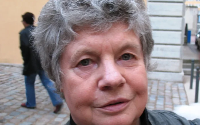 Retrato de la novelista británica A. S. Byatt, con cabello gris rizado, en una calle empedrada.